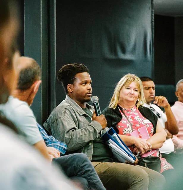 A man speaks into a microphone during a recovery group session.